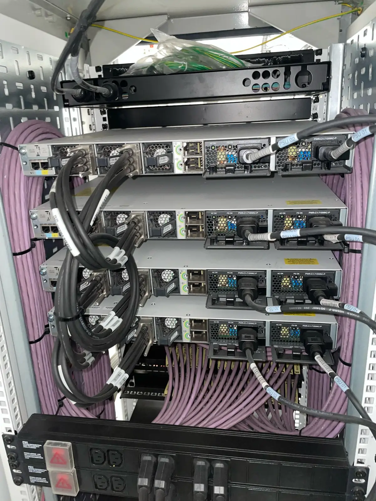 Network switches with colour-coded patch cabling in a comms rack